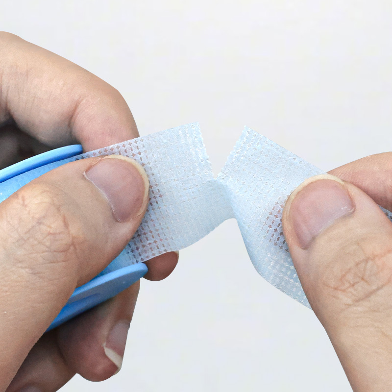 Close-up of plus-minus line on blue Kind Removal Tape showing hand tearing it easily